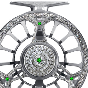 Close-up of the Diamond Drift fly reel featuring silver metalwork encrusted with diamonds and green gemstones.