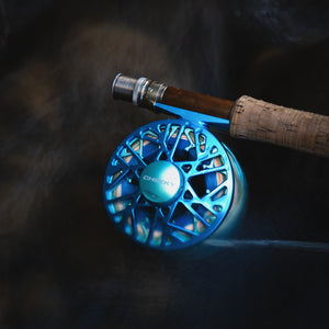 blue fly reel on a fishing rod in the water with blurred current rushing passed