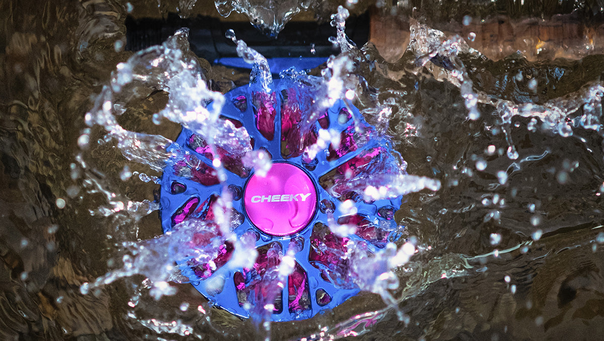A purple and pink fly reel splashing into the water