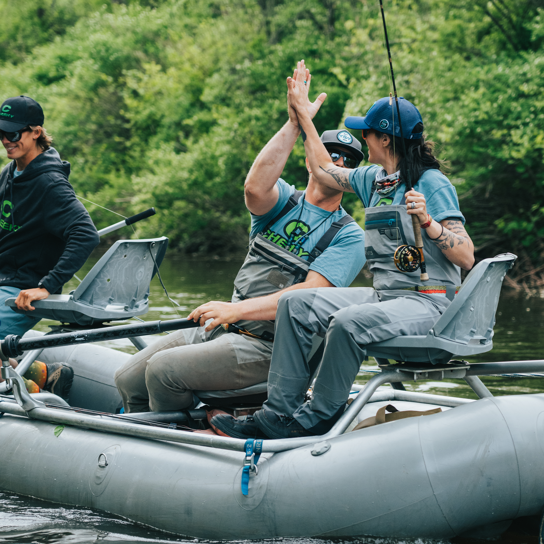 Man and women high-fiving in raft while fishing with Cheeky Launch Fly Reel